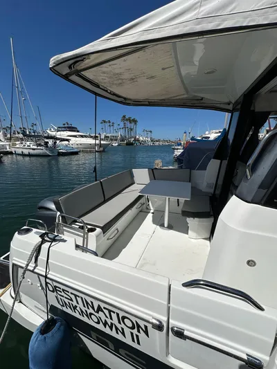 Destination Unknown II Yacht Photos Pics 2021 Jeanneau NC 895 boat docked at marina, featuring spacious seating and table.