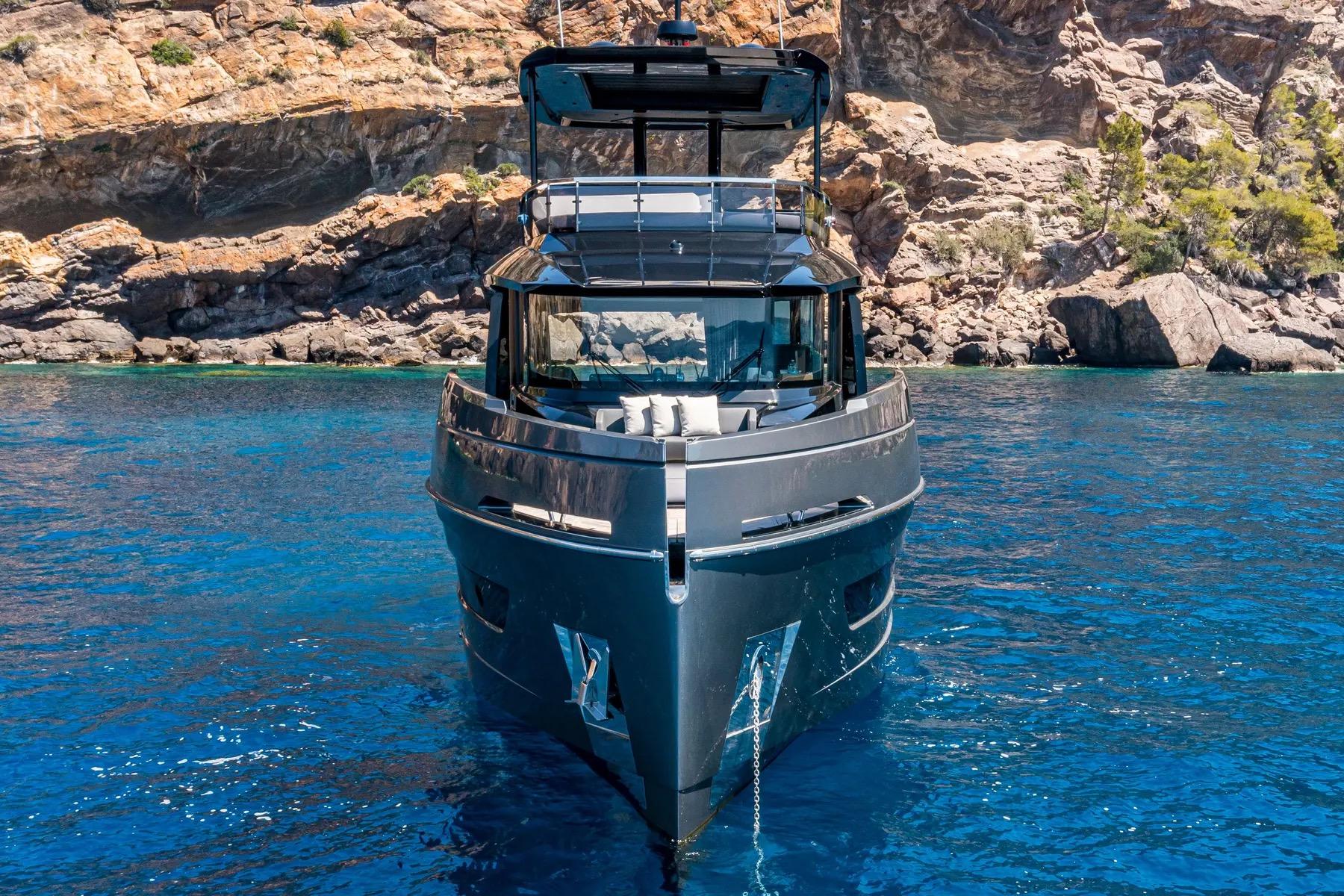 2025 Explorer 62 yacht on clear blue water near rocky coastline.