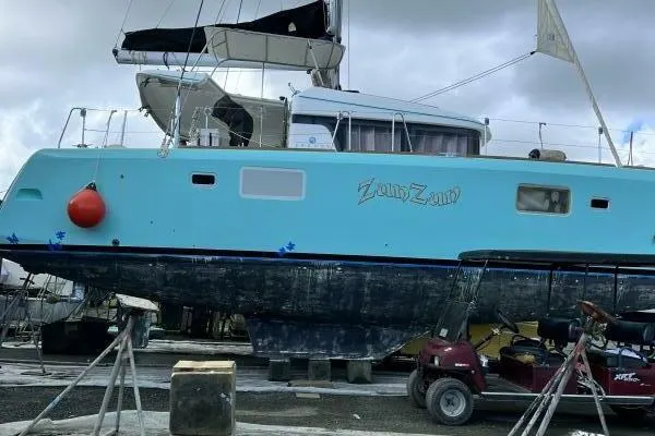 Zun Zun Yacht Photos Pics 2014 Lagoon 39 catamaran on dry dock, turquoise hull, red buoy, overcast sky.
