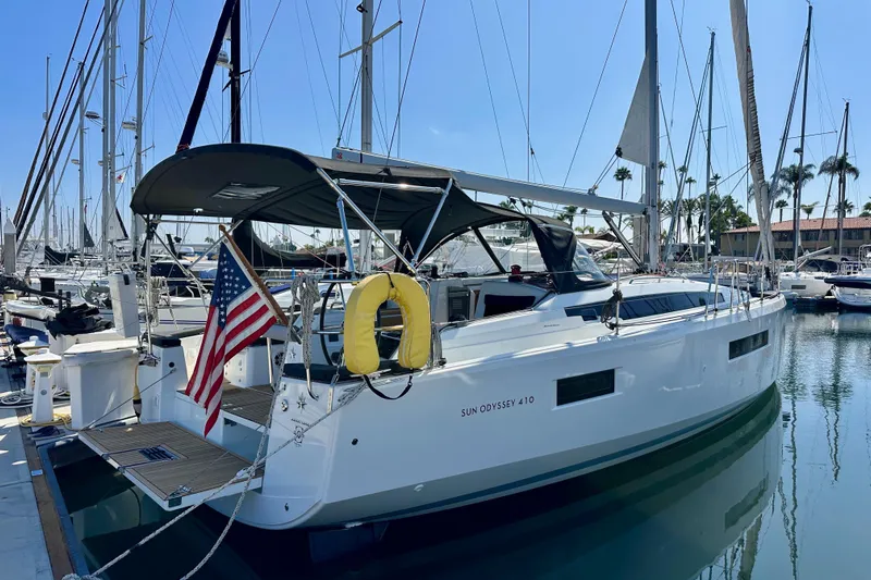 Best Day Ever Yacht Photos Pics 2022 Jeanneau Sun Odyssey 410 sailboat docked in marina with American flag.
