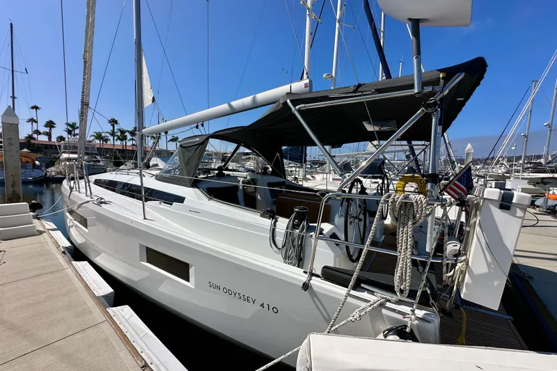 Best Day Ever Yacht Photos Pics 2022 Jeanneau Sun Odyssey 410 sailboat docked at marina under clear blue sky.