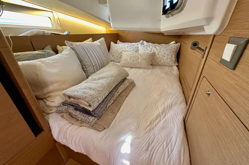 Best Day Ever Yacht Photos Pics Cozy cabin interior of 2022 Jeanneau Sun Odyssey 410 with plush bedding and wooden accents.