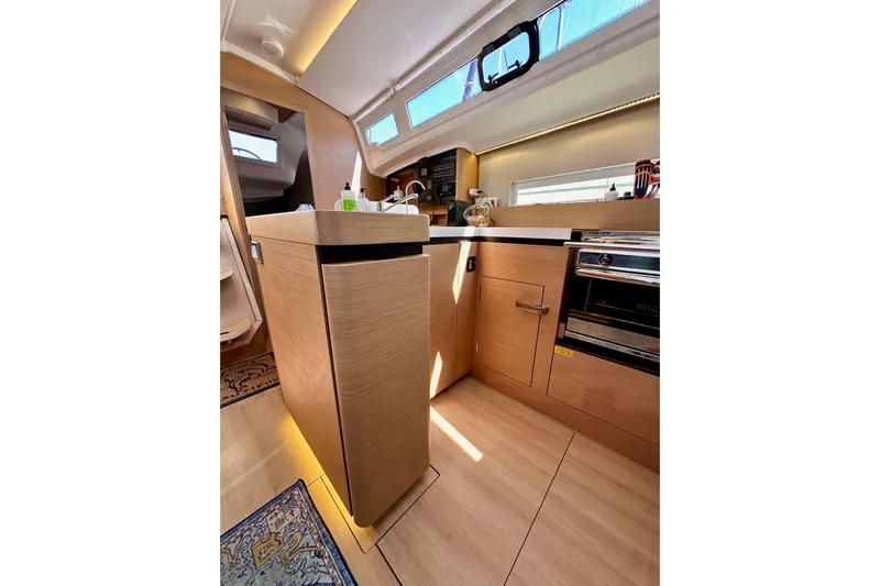 Best Day Ever Yacht Photos Pics Modern kitchen interior of 2022 Jeanneau Sun Odyssey 410 yacht, featuring wood cabinetry and appliances.