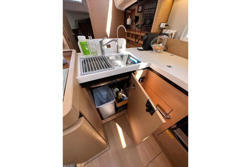Best Day Ever Yacht Photos Pics Modern kitchen area in 2022 Jeanneau Sun Odyssey 410 yacht, featuring sink and storage.