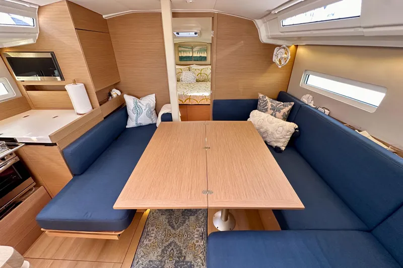Best Day Ever Yacht Photos Pics Interior of 2022 Jeanneau Sun Odyssey 410 sailboat with blue seating and wooden table.