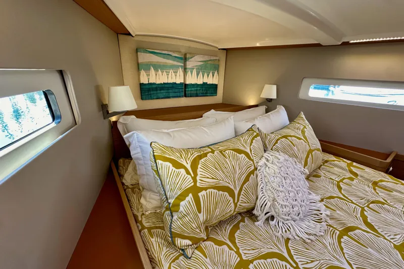 Best Day Ever Yacht Photos Pics Cozy cabin interior of 2022 Jeanneau Sun Odyssey 410 with stylish bedding and nautical decor.