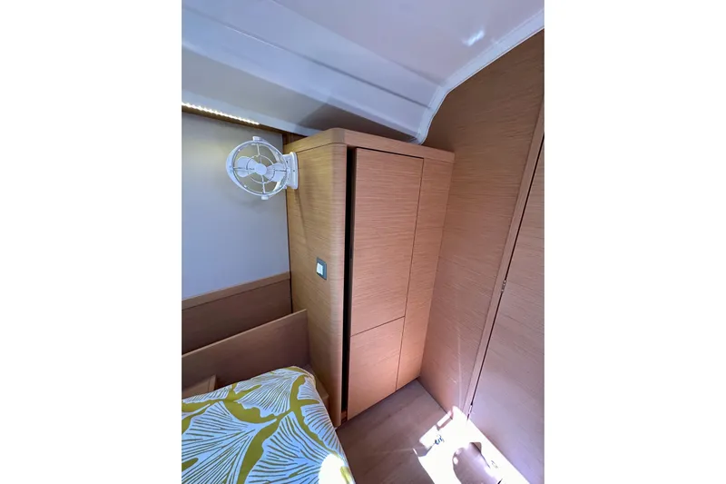 Best Day Ever Yacht Photos Pics Interior cabin of 2022 Jeanneau Sun Odyssey 410 with wooden cabinetry and wall-mounted fan.