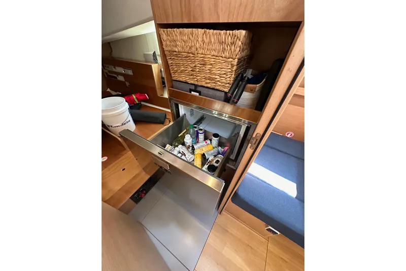Best Day Ever Yacht Photos Pics Interior of 2022 Jeanneau Sun Odyssey 410 with open storage drawer and wicker basket.