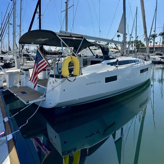 Best Day Ever Yacht Photos Pics 2022 Jeanneau Sun Odyssey 410 sailboat docked in marina with American flag.