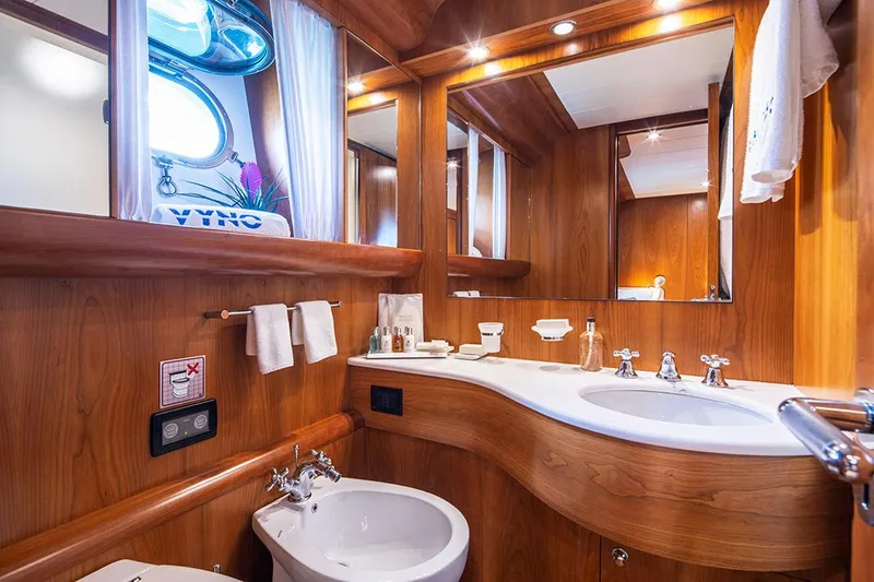  Yacht Photos Pics Luxurious wooden bathroom interior on a 2003 Canados 86 yacht, featuring elegant fixtures and mirrors.