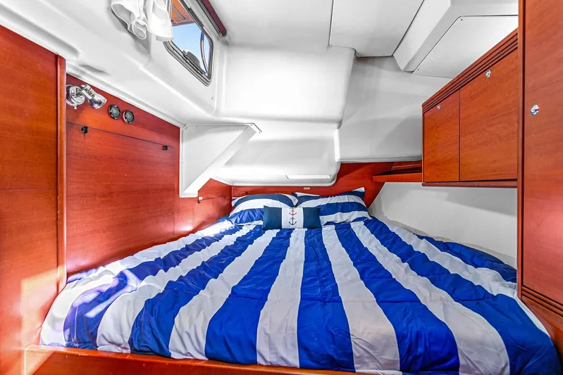La Chiricana Yacht Photos Pics Cozy cabin interior of 2011 Dufour 525 Grand Large with striped bedding and wooden cabinetry.