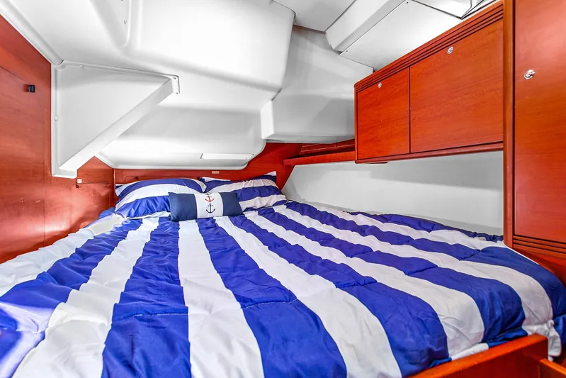 La Chiricana Yacht Photos Pics Cozy cabin interior of 2011 Dufour 525 Grand Large with striped bedding and wooden cabinets.