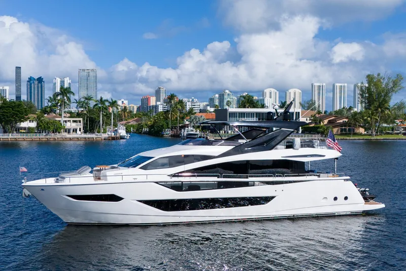 Ramaya 4 Yacht Photos Pics 2023 Sunseeker 88 Yacht cruising near city skyline, under a clear blue sky.