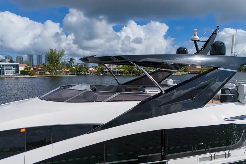 Ramaya 4 Yacht Photos Pics Luxurious 2023 Sunseeker 88 Yacht cruising on a scenic waterway under a cloudy sky.