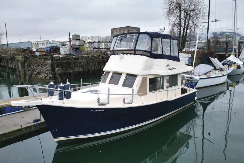 Hula Moon Yacht Photos Pics 2006 Mainship 34 Trawler docked in a marina, featuring a blue hull and enclosed flybridge.