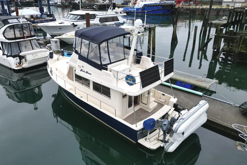 Hula Moon Yacht Photos Pics 2006 Mainship 34 Trawler docked in a marina, featuring solar panels and a dinghy.