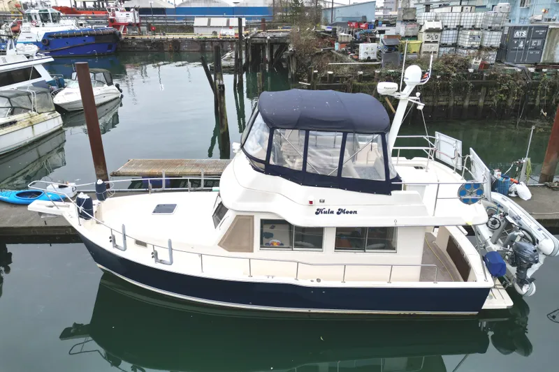 Hula Moon Yacht Photos Pics 2006 Mainship 34 Trawler docked at marina, featuring blue canopy and white hull.