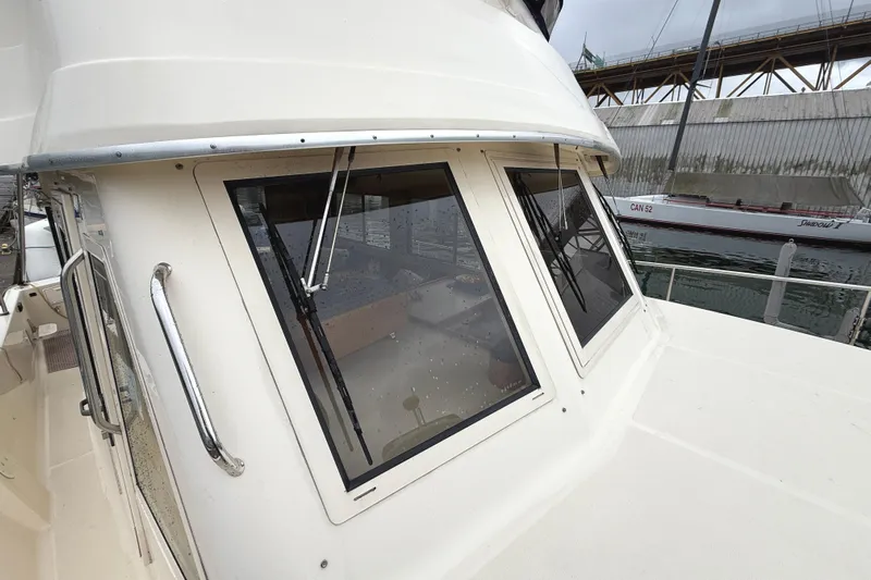 Hula Moon Yacht Photos Pics 2006 Mainship 34 Trawler with large windows and sleek design, docked near a sailboat.