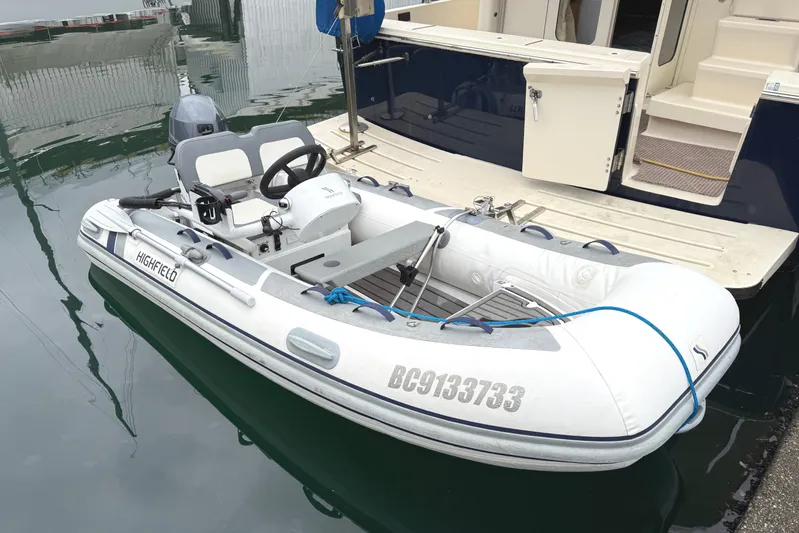 Hula Moon Yacht Photos Pics White inflatable dinghy docked beside a 2006 Mainship 34 Trawler boat.