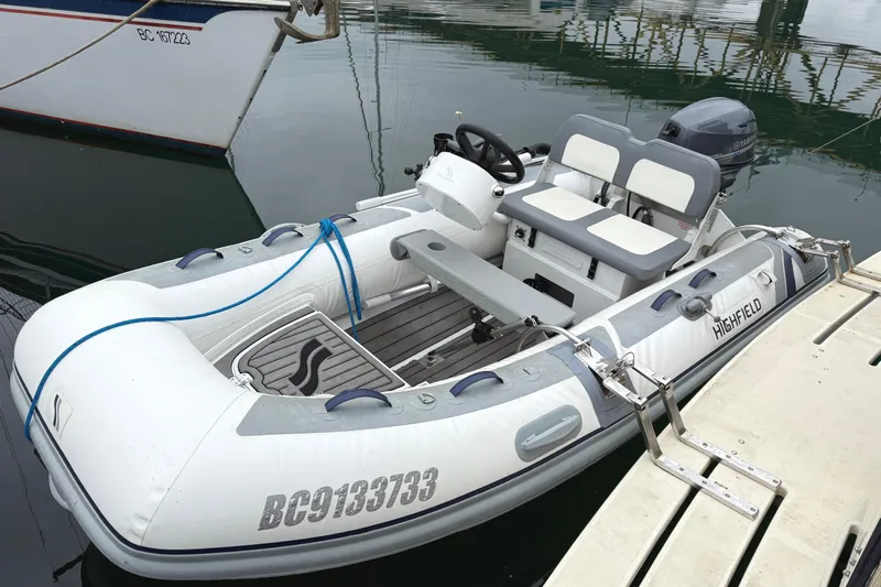 Hula Moon Yacht Photos Pics White Highfield inflatable boat docked, featuring seating and steering, near a 2006 Mainship 34 Trawler.