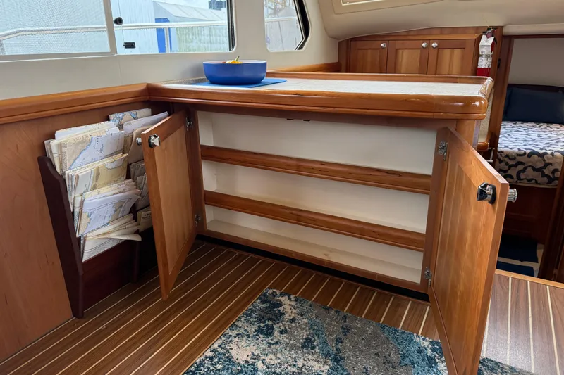 Hula Moon Yacht Photos Pics 2006 Mainship 34 Trawler interior with wooden cabinetry and nautical charts.