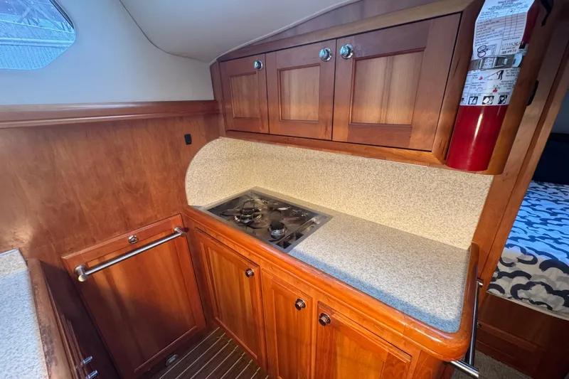 Hula Moon Yacht Photos Pics 2006 Mainship 34 Trawler kitchen with wooden cabinets and compact stove.