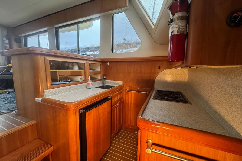 Hula Moon Yacht Photos Pics Interior of 2006 Mainship 34 Trawler, featuring a compact kitchen with wood cabinetry.