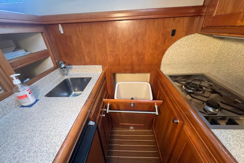 Hula Moon Yacht Photos Pics 2006 Mainship 34 Trawler kitchen with sink, stove, and wooden cabinetry.