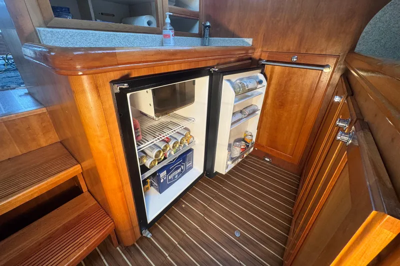 Hula Moon Yacht Photos Pics 2006 Mainship 34 Trawler interior with open fridge, wooden cabinetry, and striped flooring.