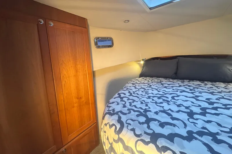 Hula Moon Yacht Photos Pics Cozy bedroom in 2006 Mainship 34 Trawler with wooden cabinet and patterned bedding.