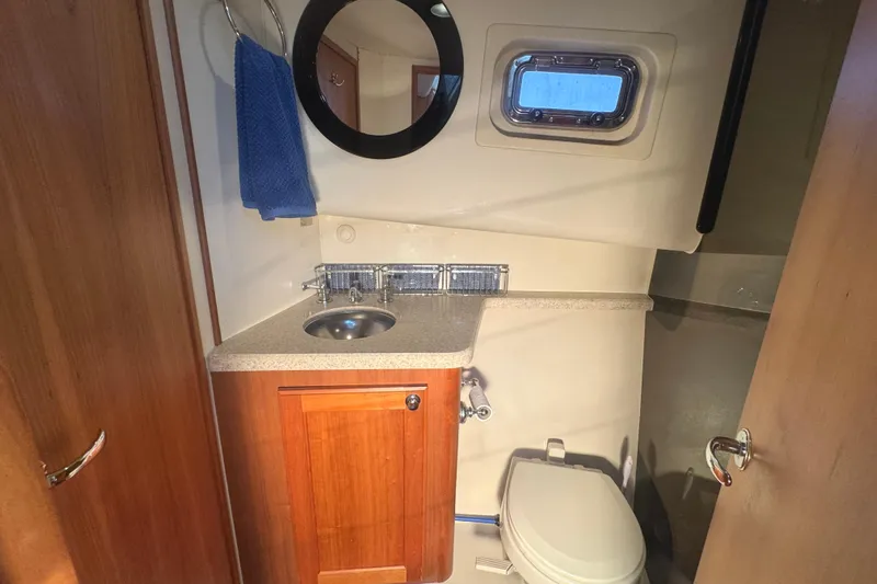 Hula Moon Yacht Photos Pics 2006 Mainship 34 Trawler bathroom with sink, toilet, mirror, and porthole window.