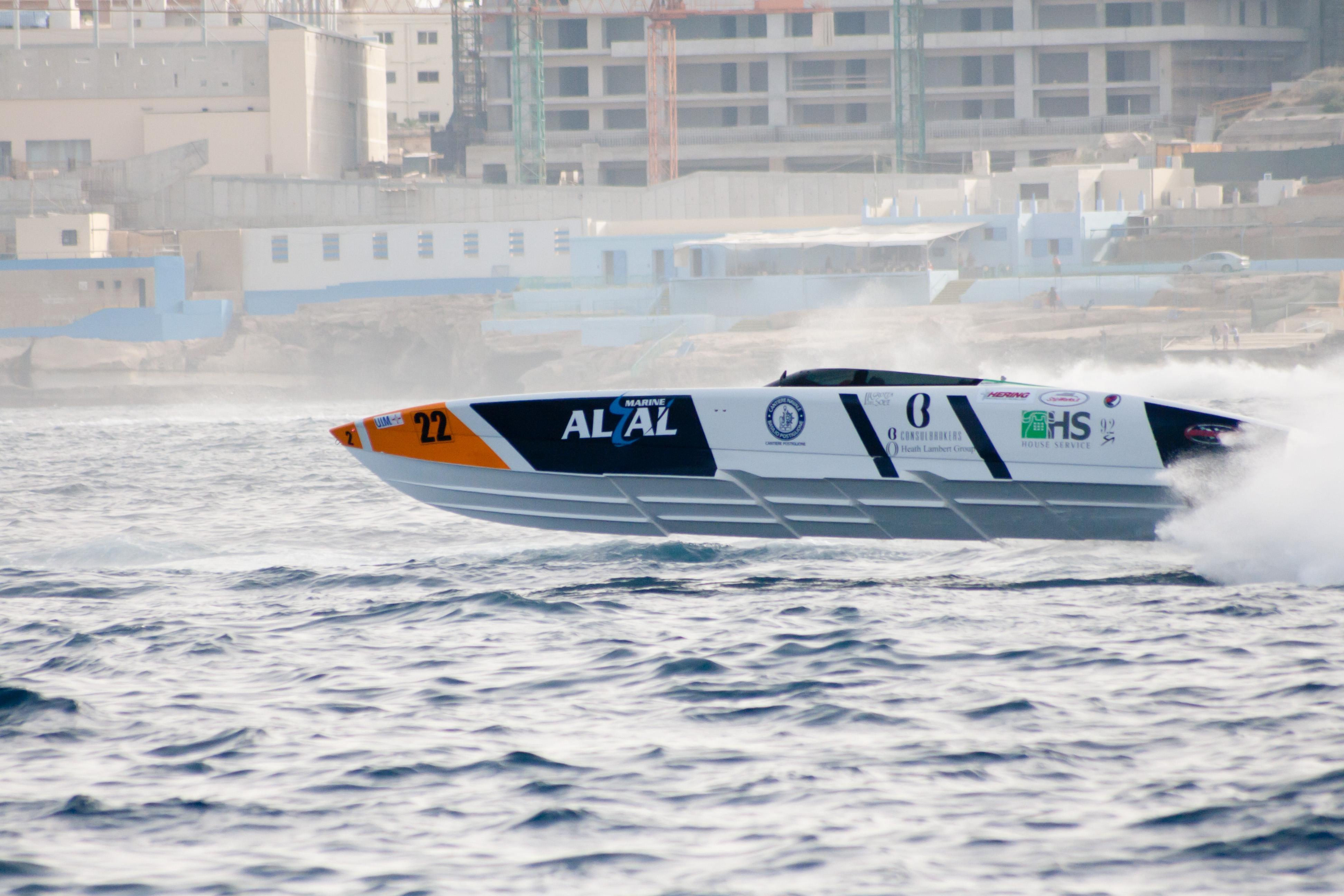 2021 Outerlimits 40 SV powerboat racing on water near urban backdrop.
