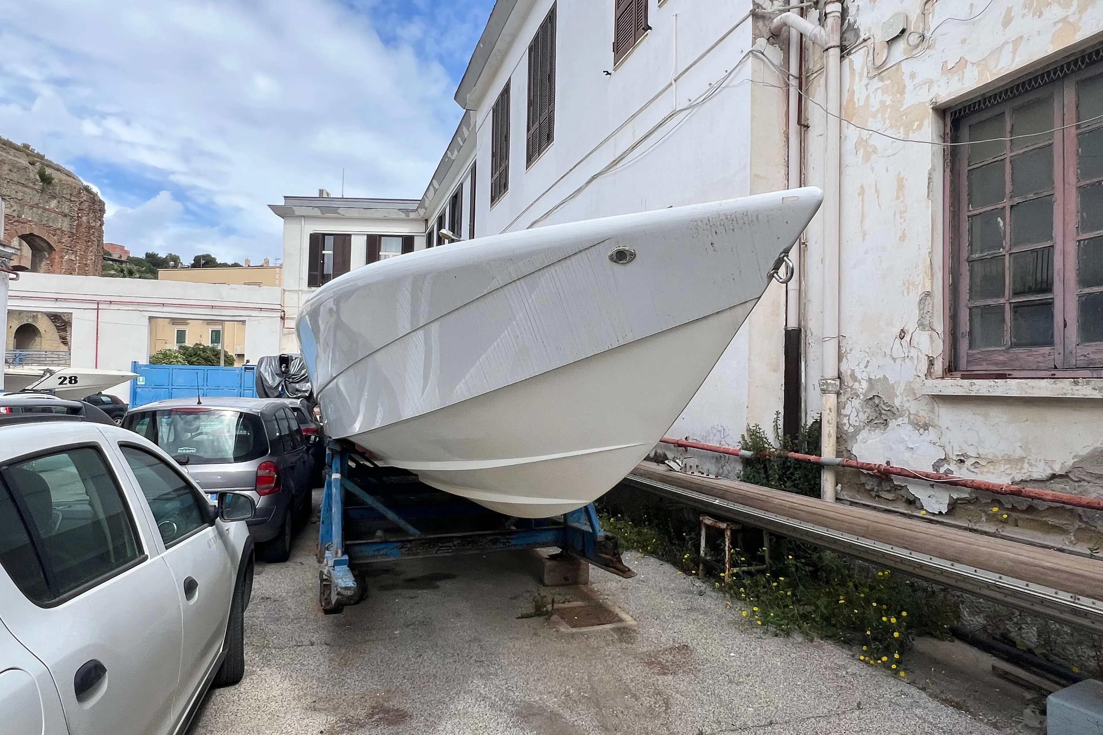 2021 Outerlimits 40 SV boat on trailer beside building, under blue sky.