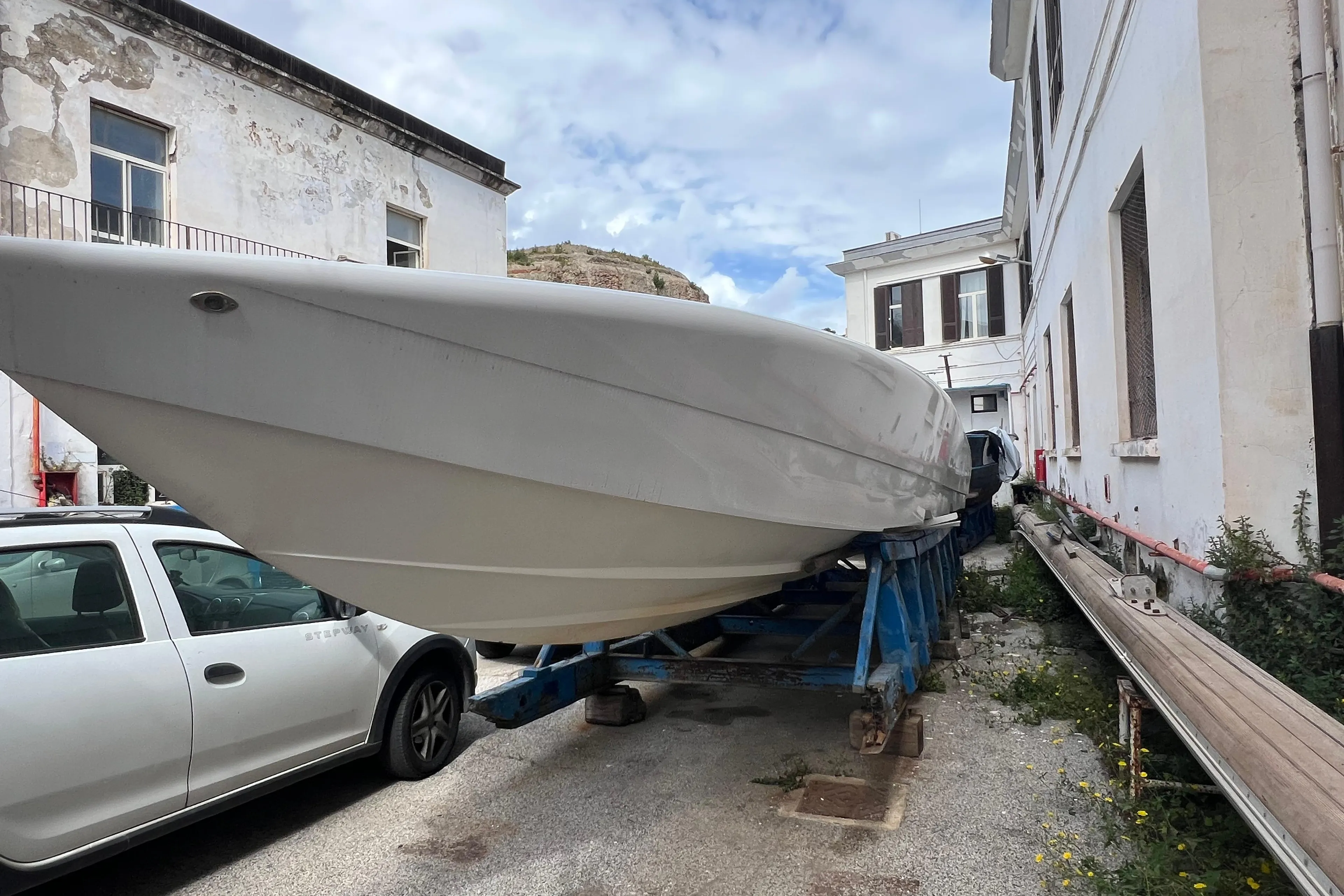 2021 Outerlimits 40 SV boat on trailer between buildings, under a partly cloudy sky.