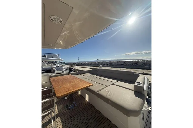  Yacht Photos Pics Luxurious 2022 Prestige 590 yacht deck with seating and table under sunny sky.