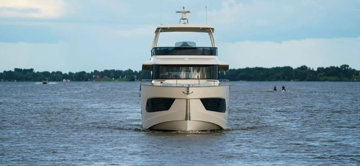 2024 Absolute 58 Navetta yacht cruising on a calm lake under a cloudy sky.