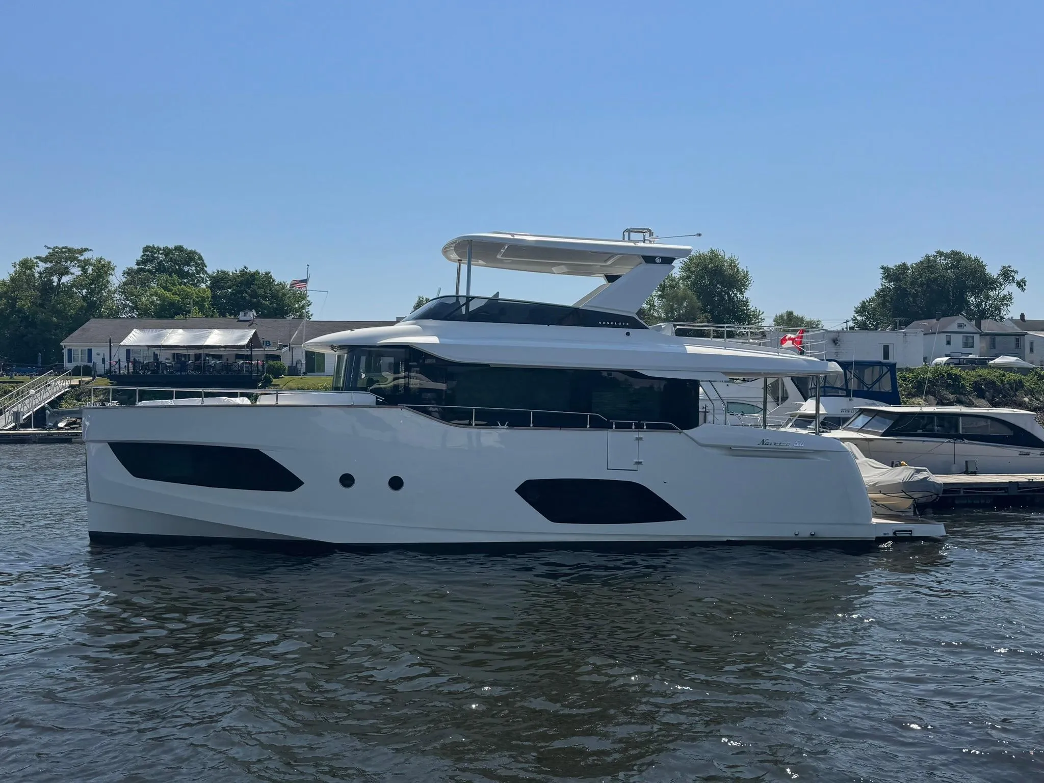 2024 Absolute 58 Navetta yacht on water, sleek design, sunny day, marina background.