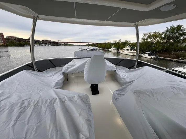  Yacht Photos Pics 2024 Absolute 58 Navetta yacht deck with covered seating, overlooking a serene waterfront.