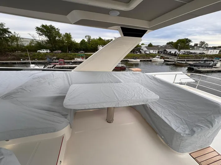  Yacht Photos Pics Outdoor seating area on 2024 Absolute 58 Navetta yacht, featuring covered table and benches.
