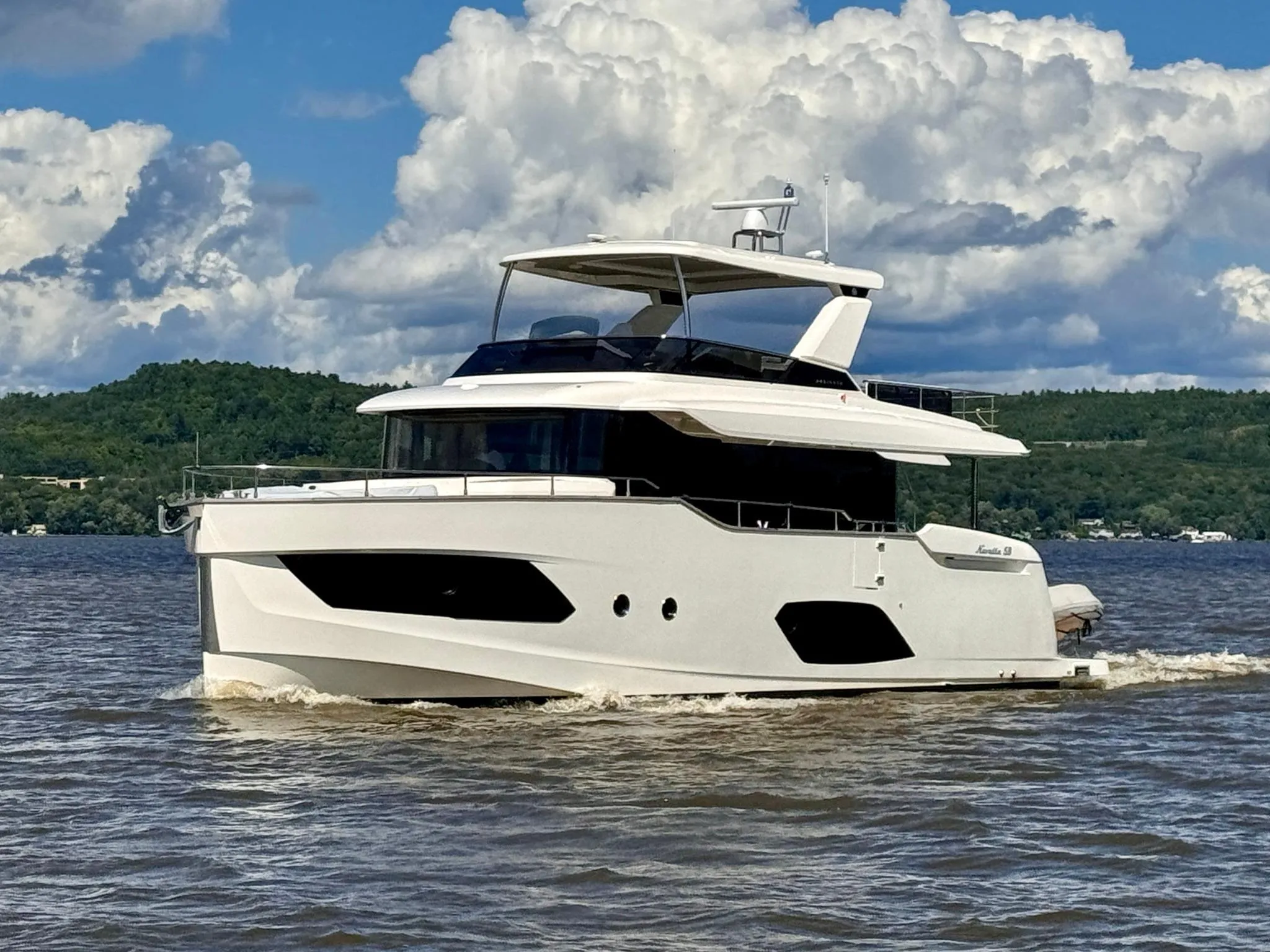 2024 Absolute 58 Navetta yacht cruising on a lake under a cloudy sky.