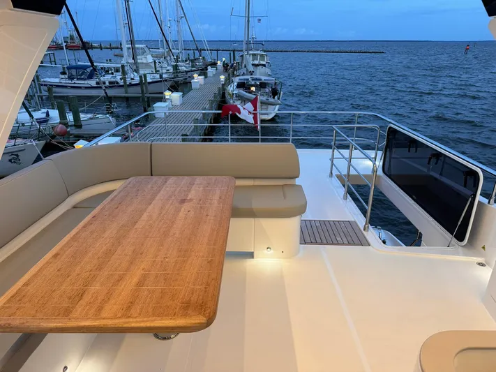  Yacht Photos Pics 2024 Absolute 58 Navetta yacht deck with wooden table, docked at marina.