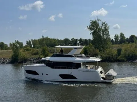  Yacht Photos Pics 2024 Absolute 58 Navetta yacht cruising on a calm river under a clear blue sky.