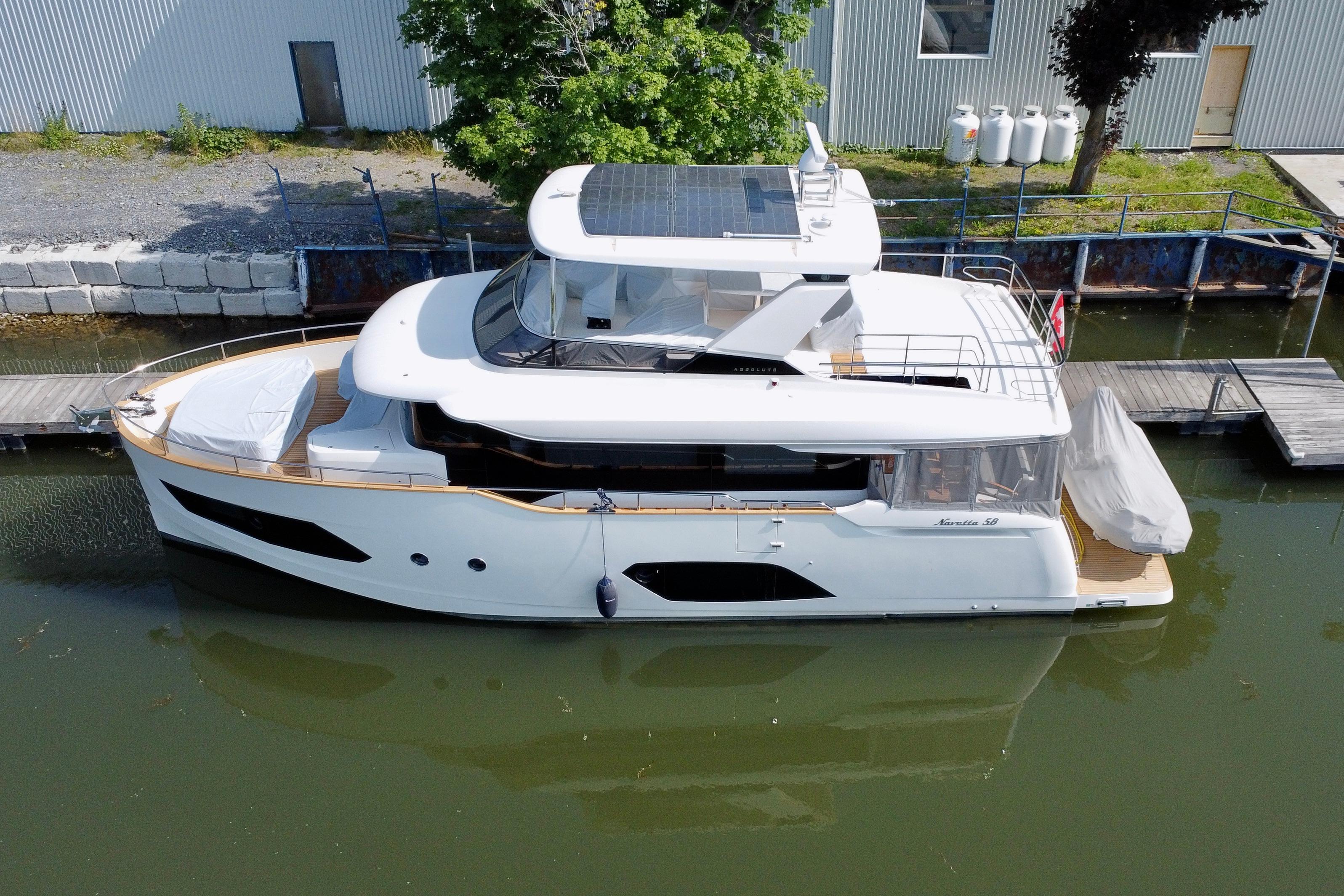 2024 Absolute 58 Navetta yacht docked in a serene marina setting.