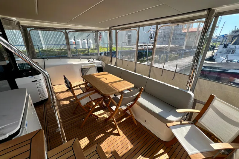  Yacht Photos Pics 2024 Absolute 58 Navetta yacht interior with wooden deck, dining table, and seating area.