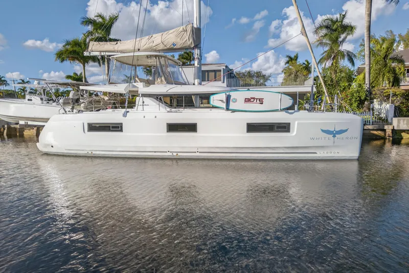 White Heron Yacht Photos Pics 2021 Lagoon 46 Owner's Version catamaran docked, featuring sleek design and paddleboard on deck.