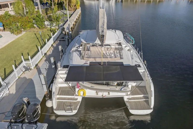 White Heron Yacht Photos Pics Aerial view of 2021 Lagoon 46 Owner's Version catamaran docked by a lush waterfront.