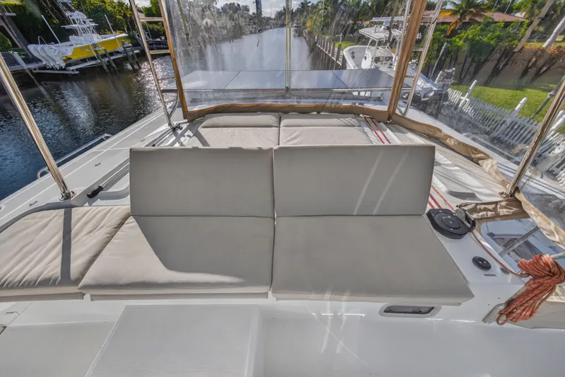 White Heron Yacht Photos Pics Luxurious seating area on 2021 Lagoon 46 Owner's Version catamaran, docked by a scenic canal.