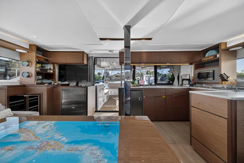White Heron Yacht Photos Pics Luxurious interior of 2021 Lagoon 46 Owner's Version yacht with modern kitchen and navigation table.