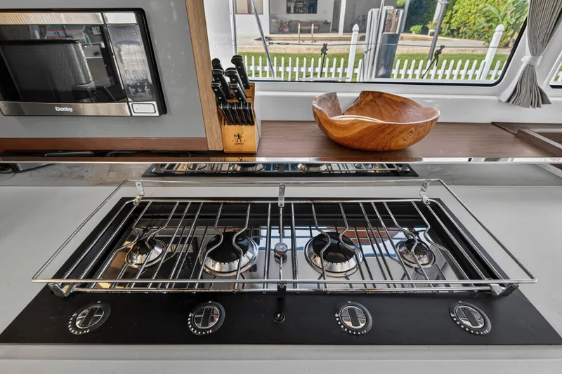 White Heron Yacht Photos Pics Modern kitchen in 2021 Lagoon 46 yacht with stove, microwave, and wooden bowl.