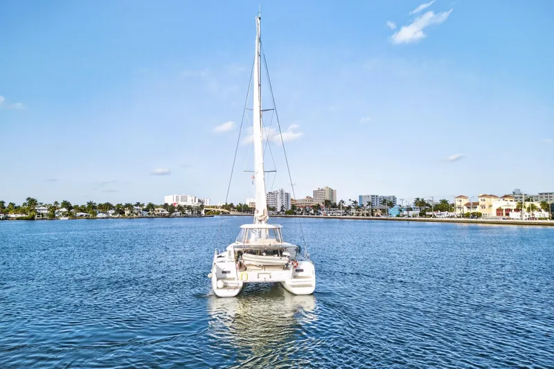 White Heron Yacht Photos Pics 2021 Lagoon 46 Owner's Version catamaran sailing in a sunny coastal cityscape.